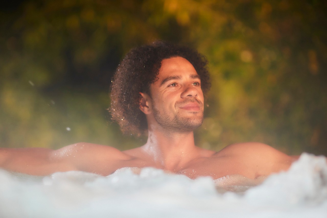 Man soaking in a bubbling outdoor hot tub.